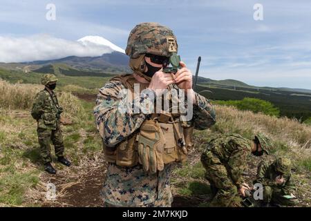 USA Marinekapitän Kurt James, Center, ein gemeinsamer Terminal-Angriffscontroller mit 31. Marine Expeditionary Unit (MEU), blickt während einer simulierten Nahübung in Gotemba, Japan, durch einen Kompass. Am 10. Mai 2022. Die MEU von 31., die einzige fortlaufend nach vorn entsandte MEU des Marine Corps, bietet eine flexible und tödliche Truppe, die bereit ist, eine breite Palette militärischer Operationen als führende Krisenreaktionstruppe in der Region Indo-Pazifik durchzuführen. Stockfoto