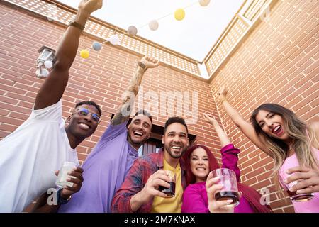 Aufgeregte Freunde feiern und Spaß haben, während sie eine Party im Freien veranstalten. Freundschaftskonzept. Stockfoto