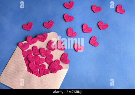 Umschlag und rosa Herzen auf blauem Hintergrund. Valentinstag, Liebe, Jubiläumskonzept. Stockfoto