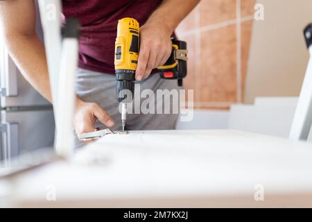 Das Einschrauben einer selbstschneidenden Schraube in ein Befestigungsloch aus Metall auf einem Holzstreifen mit einem Schraubendreher ist das Werk eines Zimmermanns. Platz zum Kopieren. Stockfoto