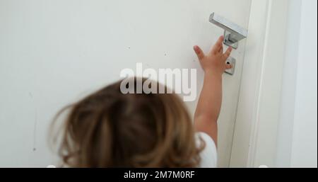 Baby versucht Türknauf zu erreichen. Ein Kind auf den Zehen, das door2 Jahre alt ist Stockfoto