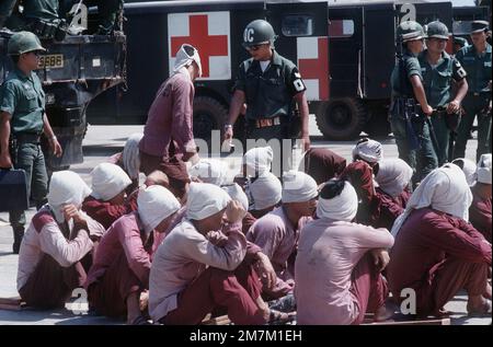 Vietcong-Kriegsgefangene sitzen unter den wachsamen Augen der südvietnamesischen Militärpolizei auf der Rampe des Luftwaffenstützpunktes Tan Son Nhut. Die Kriegsgefangenen werden nach Loc Ninh, Südvietnam, geflogen, für den Gefangenenaustausch zwischen den Militärs der Vereinigten Staaten/Südvietnam und Nordvietnam/Vietcong. Subjekt Operation/Serie: HOMECOMING-Basis: Saigon-Land: Südvietnam Stockfoto