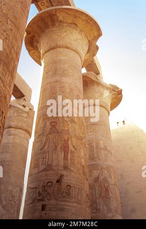 Senkrechte, niedrige Nahaufnahme einer Reihe von Säulen mit geschnitzter Hieroglyphe im Tempel von Krnak in Luxor, Ägypten Stockfoto