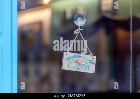 Nahaufnahme eines hölzernen offenen Schilds an der Glasvordertür eines Friseurladens. Stockfoto