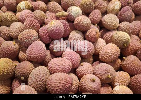 Nahaufnahme eines Stapels Lychees zum Verkauf an einem Marktstand. Stockfoto