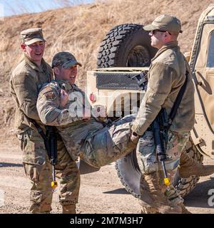 Airman 1. Class Christian Adkins (links) und Tech. Sgt. Lucas Keppere (rechts), 341. Bauingenieure-Geschwader, Carry Tech. Sgt. Adam Beaudoin, 341. CES-Mitglied, simuliert eine Verletzung durch einen Bodenangriff während einer CES-Übung am 10. Mai 2022 am Luftwaffenstützpunkt Malmstrom, Mont. Die Gruppe lernte über Landnavigation, individuelle Bewegungstechniken, Verteidigungspositionen, Feldsanitäranlagen und Nachtsichtgeräte. Stockfoto