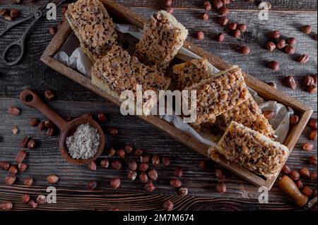 Nusskuchen mit karamellisierten Haselnüssen auf Holzhintergrund. Flach verlegt Stockfoto