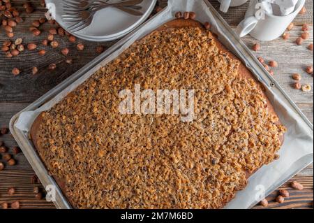 Haselnusskuchen frisch und hausgemacht, auf einem Backblech auf einem Holztisch gebacken. Flach verlegt Stockfoto