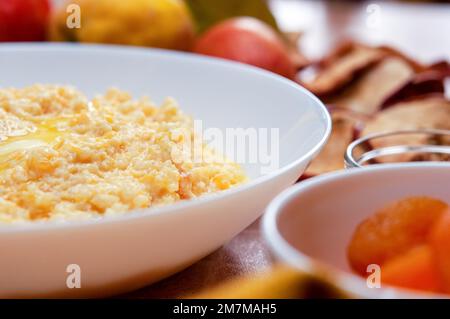 Kürbisbrei mit Hirse, Milch und Zimt. Nahaufnahme von Kürbisbrei mit Hirse, serviert in einer weißen Schüssel, selektiver Fokus, horizontaler Schuss. Stockfoto