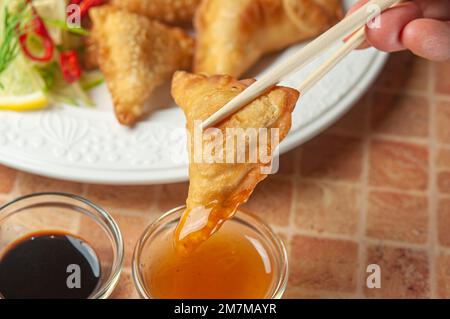 Chinesische Wontons mit süßer Chili Dip Sauce und Hackstangen. Asiatische gebratene Knödel mit Sojasauce auf weißem Gericht. Stockfoto