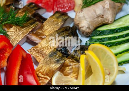 Scheiben geräucherter Fischmakrele oder scomber auf einem weißen Gericht mit Zitrone, Apfel, Ingwer, Gurke, Paprika, Grapefruit, Dill, Draufsicht. Stockfoto