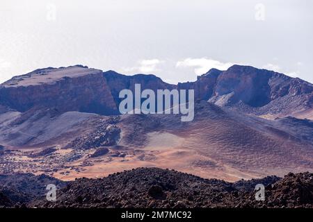 Teleaufnahmen des Vulkans Caldera, in der Ferne blau und lila getönt, hinter braunem vulkanischem Boden Stockfoto