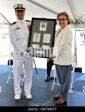 Cecilla Guillot überreicht Lieutenant Eli Maurer ein Geschenk während der Zeremonie der Küstenwache Cutter Pablo Valent in der Coast Guard Sector St. Petersburg, Florida, 11. Mai 2022. Guillot ist Sponsor und Großnichte von Pablo Valent, Namensgeber des 48. Jahrhunderts. Ein Schiff der Sentinel-Klasse unter dem Kommando von Lieutenant Maurer. USA Foto der Küstenwache von Petty Officer 1. Klasse Ayla Hudson. Stockfoto