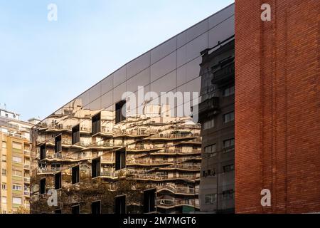 Die Appartementgebäude spiegeln sich in einem Gebäude mit verspiegelter Fassade wider Stockfoto