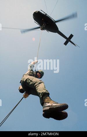 Ein Soldat der US-Armee abseilt sich von einem UH-1 Irokois Helikopter während einer Trainingsübung ab. Land: Unbekannt Stockfoto