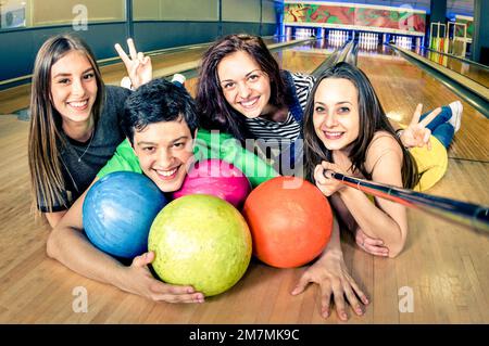 Beste Freunde, die Selfie-Stäbchen benutzen, um ein Foto auf der Bowlingbahn zu machen - Freundschaftskonzept mit jungen, verspielten Menschen, die Spaß miteinander haben - Weiche Konzentration auf den Kerl Stockfoto