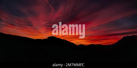 Eine Silhouettenaufnahme der Berge unter einem dramatischen Sonnenuntergang Stockfoto