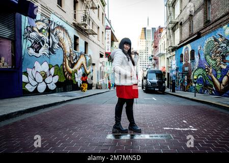 Junge Frau, die in der Straße in Chinatown San Francisco steht Stockfoto