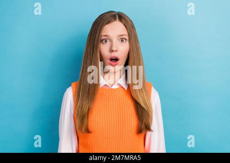 Foto eines jungen schockierten Teenagers Mädchen tragen gestrickte orangefarbene Uniform mit offenem Mund sprachlose harte Prüfung Jahresende Test isoliert auf blauem Hintergrund Stockfoto