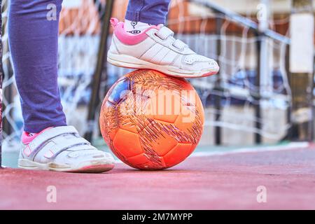 Nahaufnahme der Füße einer lateinischen Torhüterin auf einem Fußballtor mit Fußballball Stockfoto
