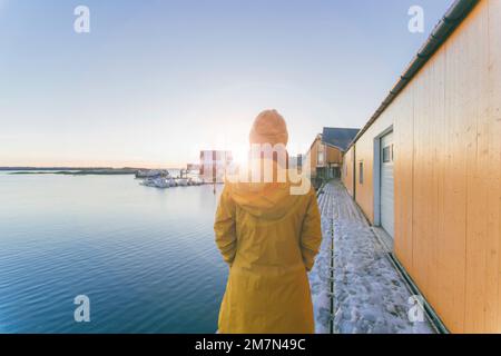 Junge Frau mit gelbem Regenmantel in Norwegen, Lofoten, Fischerdorf Stockfoto