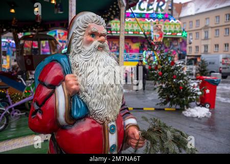 Weihnachtsmann-Figur vor einem Karussell auf einem Weihnachtsmarkt am Tag im Dezember in Mecklenburg-Vorpommern. Stockfoto