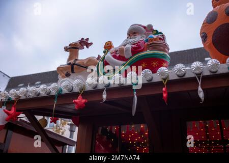 Weihnachtsmann-Figur mit Schlitten auf dem Dach an dem Tag im Dezember. Stockfoto