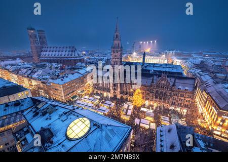 Verschneiter Marienplatz mit Weihnachtsmarkt, Rathaus und Frauenkirche in der Dämmerung. München, Bayern, Deutschland. Stockfoto