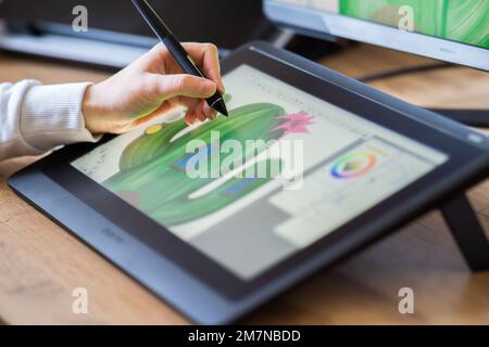 Nahaufnahme der Hand eines Mädchens, die auf einem digitalen Tablet zeichnet. Mädchen, das von zu Hause aus als Grafikdesignerin arbeitet. Junge Frau, die auf einem digitalen Zeichenbrett zeichnet Stockfoto