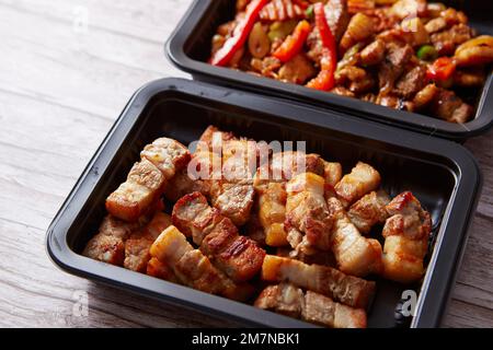 Gebratenes Schweinefleisch und scharfes Schweinefleisch in Behältern Stockfoto