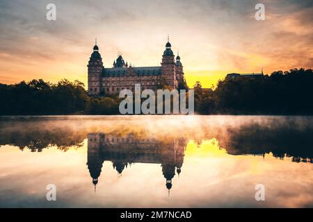 Die Burg oder das Schloss Johannisburg in Aschaffenburg im Frühling. Reflexion am Main, Nebel bei Sonnenaufgang und unglaubliche Atmosphäre. Stockfoto