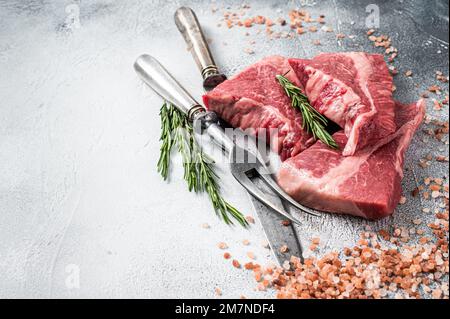 Silberseidenfilet-Rindfleisch geschnitten, rohes Fleisch auf dem Metzgertisch mit Kräutern. Weißer Hintergrund. Draufsicht. Speicherplatz kopieren. Stockfoto