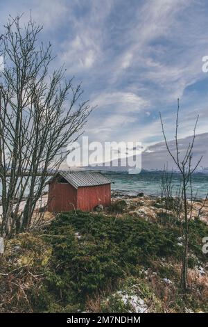 Traditionelles Bootshaus in Lofoten, Norwegen, typische Fjordlandschaft mit Blick auf die Berge und das Meer Stockfoto