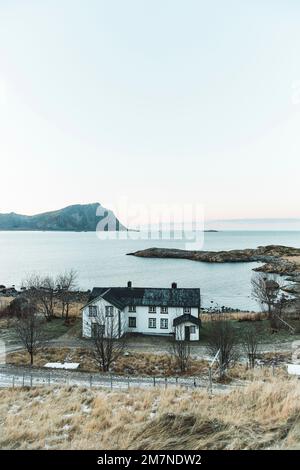 Abgelegenes Wohnhaus auf dem Anwesen in abendlicher Atmosphäre, Fjordlandschaft mit kleinen Inseln, Abgeschiedenheit von der Außenwelt, Vesteralen, Norwegen Stockfoto