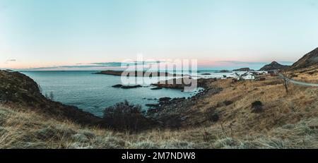 Abgelegenes Fischerdorf mit typischen nordischen Hütten und Häusern in abendlicher Atmosphäre, Fjordlandschaft mit kleinen Inseln, Abgeschiedenheit von der Außenwelt, Vesteralen, Norwegen, Panoramabild Stockfoto