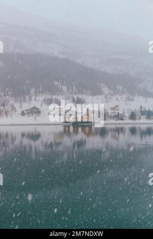 Rote und gelbe Rorbu Häuser an der Küste, Fischerdorf in Vesteralen, Norwegen, Schneefall, Winter Stockfoto