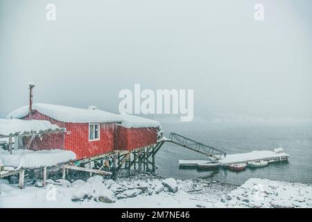 Rote und gelbe Rorbu Häuser an der Küste, Fischerdorf in Vesteralen, Norwegen, Schneefall, Winter Stockfoto