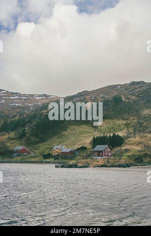 Einsame Häuser am Fjord in Norwegen, typische Fjordlandschaft mit kleinen Inseln, Abgeschiedenheit von der Außenwelt, rotes Haus am Meer Stockfoto