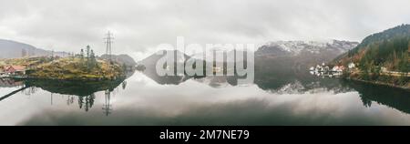 Panoramablick auf den Fjord mit einer Gruppe von Inseln, Fischerhütten, Häusern, Booten, Strommasten in Norwegen, Landschaft mit einsamem Fischerdorf, typisch f Stockfoto