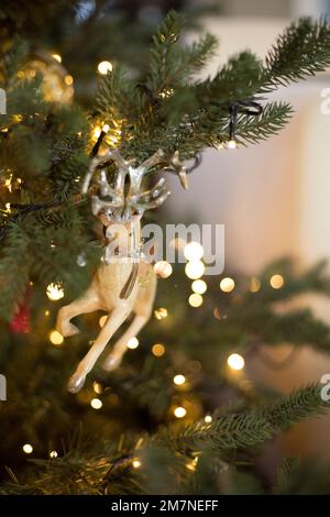 Weihnachtsbaumfigur in Rentierform in beleuchtetem Weihnachtsbaum Stockfoto