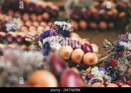 Blumendekoration auf Zwiebelgeflecht, traditionelle Zibelemärit, Zwiebelmarkt in Bern, Schweiz, Nahaufnahme, essbare Zwiebeln (Allium cepa) Stockfoto