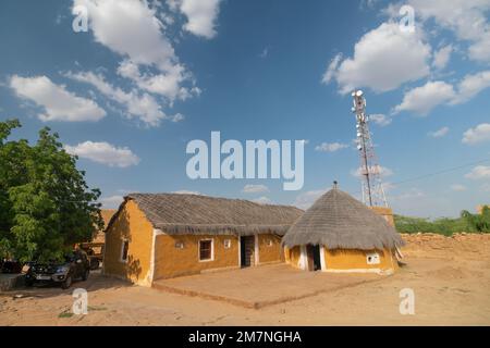 Jaisalmer, Rajasthan, Indien - 15. Oktober 2019 : bunte Hütten im Dorf Rajsathani, Jaisalmer, Indien. Blauer Himmel und weiße Wolken Hintergrund. Stockfoto