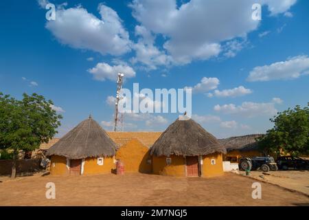 Jaisalmer, Rajasthan, Indien - 15. Oktober 2019 : bunte Hütten im Dorf Rajsathani, Jaisalmer, Indien. Blauer Himmel und weiße Wolken Hintergrund. Stockfoto