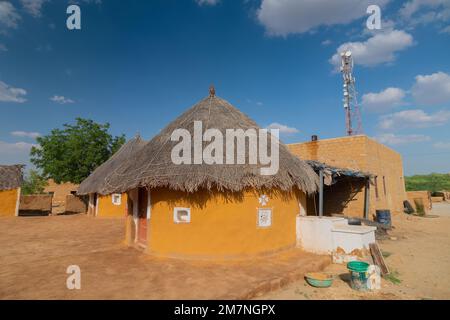 Jaisalmer, Rajasthan, Indien - 15. Oktober 2019 : bunte Hütten im Dorf Rajsathani, Jaisalmer, Indien. Blauer Himmel und weiße Wolken Hintergrund. Stockfoto