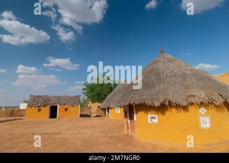 Jaisalmer, Rajasthan, Indien - 15. Oktober 2019 : bunte Hütten im Dorf Rajsathani, Jaisalmer, Indien. Blauer Himmel und weiße Wolken Hintergrund. Stockfoto