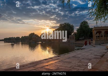 Die Sonne geht hinter dem Haupteingang des Gadisar Sees, Jaisalmer, Rajasthan, Indien unter. Historischer künstlicher See, einst nur eine Wasserressource für die Stadt Jaisalmer. Stockfoto