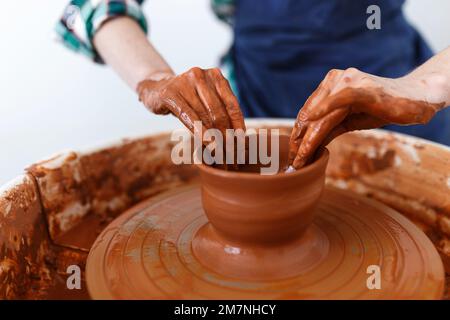 Zugeschnittenes Bild eines nicht wiedererkennbaren weiblichen Keramikmachers, das mit dem Keramikrad in Cozy Workshop arbeitet, macht eine Vase oder Tasse der Zukunft, kreatives Handwerk für Menschen Stockfoto