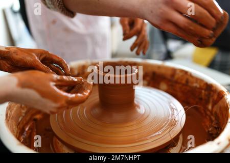 Zugeschnittenes Bild eines nicht wiedererkennbaren weiblichen Keramikmachers, das mit dem Keramikrad in Cozy Workshop arbeitet, macht eine Vase oder Tasse der Zukunft, kreatives Handwerk für Menschen Stockfoto