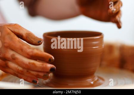 Zugeschnittenes Bild eines nicht wiedererkennbaren weiblichen Keramikmachers, das mit dem Keramikrad in Cozy Workshop arbeitet, macht eine Vase oder Tasse der Zukunft, kreatives Handwerk für Menschen Stockfoto