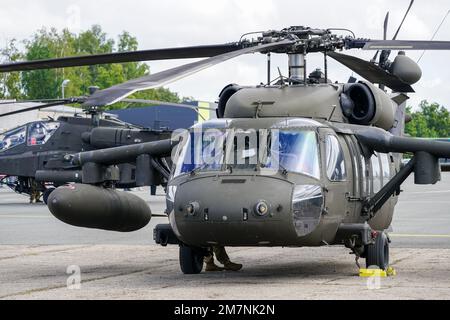 Liepaja, Lettland - 7. August 2022: US Army Sikorsky UH-60 Black Hawk und Apache AH-64D Militärhubschrauber nach der Landung am Flughafen, Vorderansicht Stockfoto